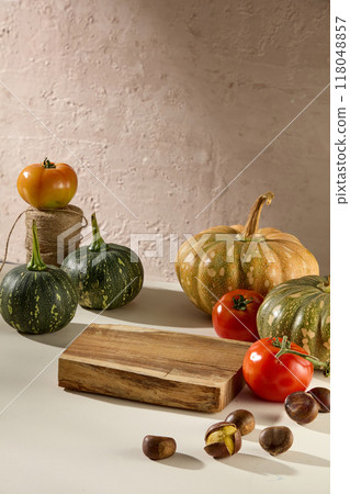 Typical autumn fruits and nuts: pumpkins, ripe tomatoes and chestnuts decorated with a wooden panel on a brown background. Advertising photo with autumn concept Typical autumn fruits and nuts: pumpkins, ripe tomatoes and chestnuts decorated with a wooden panel on a brown background. Advertising photo with autumn concept 118048857