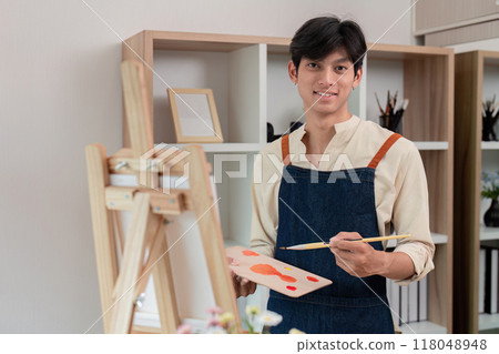 Young artist preparing canvas for painting in home studio 118048948