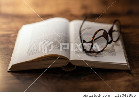 打開書,古色古香的木桌上的眼鏡 打開書,古色古香的木桌上的眼鏡 118048999