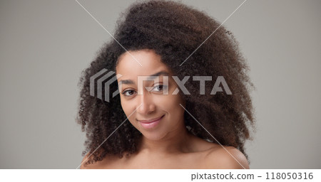 Beauty and healthcare - beautiful African American woman with curly afro hairstyle and clean, healthy skin touching her face, neck, shoulders, looking at the camera with a calm look and a slight smile Beauty and healthcare - beautiful African American woman with curly afro hairstyle and clean, healthy skin touching her face, neck, shoulders, looking at the camera with a calm look and a slight smile 118050316