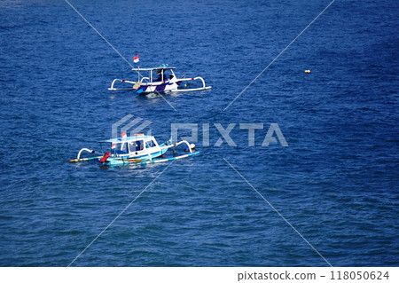 Two traditional fishing boats are anchored in the waters of Pantai Senggigi, Lombok, Indonesia Two traditional fishing boats are anchored in the waters of Pantai Senggigi, Lombok, Indonesia 118050624