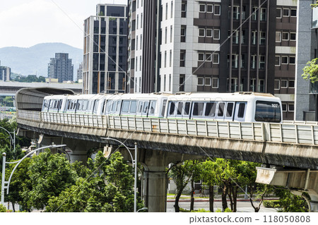 View of a Wenhu or Brown line train running on the elevated track of the Taipei Mass Rapid Transit System with the building background. 118050808