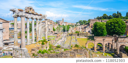 Visitors admire the ancient columns of the Saturn Temple located in the Roman Forum, a significant historical site in Rome, Italy, rich with centuries of history and culture. 118052303