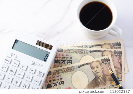 A 10,000 yen bill with a portrait of Yukichi Fukuzawa, a calculator, a pen, and a coffee cup with freshly brewed coffee. A 10,000 yen bill with a portrait of Yukichi Fukuzawa, a calculator, a pen, and a coffee cup with freshly brewed coffee. 118052587