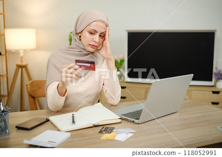 A woman is sitting at a desk with a laptop and a stack of credit cards A woman is sitting at a desk with a laptop and a stack of credit cards 118052991