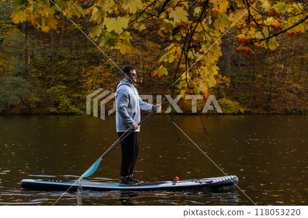 Man Paddleboarding in Autumn Lake 118053220