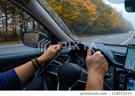 Person Driving by the road at foggy autumn highway Person Driving by the road at foggy autumn highway 118053233