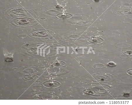 Bubbles forming in a puddle of water while raining. A close-up of the circular ripples and bubbles created by raindrops hitting the surface of the water. Bubbles forming in a puddle of water while raining. A close-up of the circular ripples and bubbles created by raindrops hitting the surface of the water. 118053377