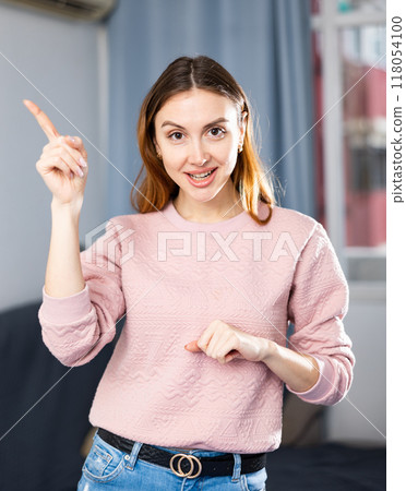 Portrait of an emotional girl pointing her finger at something in apartment Portrait of an emotional girl pointing her finger at something in apartment 118054100