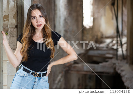 Young woman in jeans and black tee shirt posing in ruined building 118054128