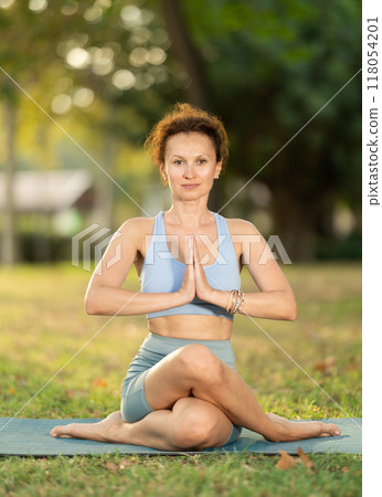 Lotus pose - slim woman doing yoga outdoors in park Lotus pose - slim woman doing yoga outdoors in park 118054201