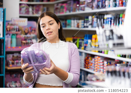 Young girl buying set of skin and haircare products in beauty boutique Young girl buying set of skin and haircare products in beauty boutique 118054223