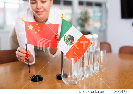 Unrecognizable girl sets midget flags of Mexico and China before international negotiations Unrecognizable girl sets midget flags of Mexico and China before international negotiations 118054234