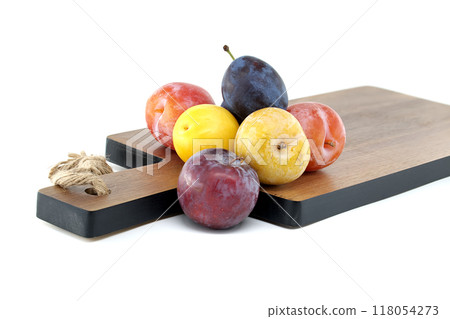 Fresh, colorful plums on a wooden cutting board showcasing vibrant fruit variety Fresh, colorful plums on a wooden cutting board showcasing vibrant fruit variety 118054273
