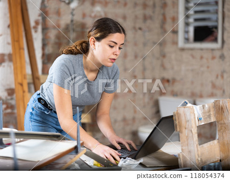 Woman with laptop on indoor construction site 118054374