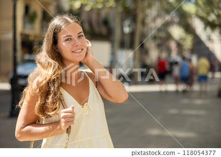 Portrait of a young girl in a light summer dress on city street during the day Portrait of a young girl in a light summer dress on city street during the day 118054377
