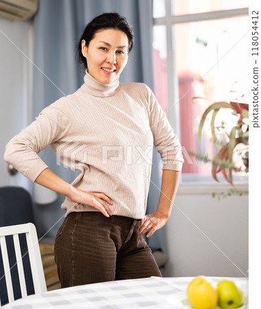 Positive woman posing at table at home 118054412