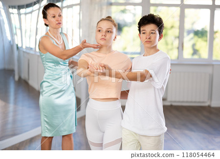 Dance lesson - teacher teaches teenage girl and boy to dance tango in studio 118054464