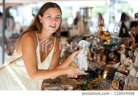 Female traveler buyer chooses ceramic antiquarian porcelain shepherdess 118054496