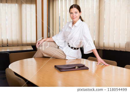 Portrait of businesswoman sitting at desk in office Portrait of businesswoman sitting at desk in office 118054499
