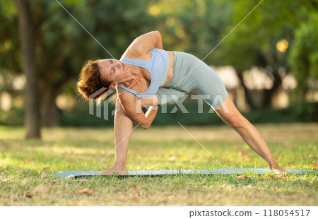 Woman practicing yoga in garden, performing Anjaneyasana, or Crescent Moon Pose 118054517