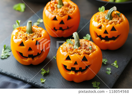 Stuffed orange bell peppers carved with jack-o'-lantern faces, filled with savory mixture. Halloween food concept Stuffed orange bell peppers carved with jack-o'-lantern faces, filled with savory mixture. Halloween food concept 118054568