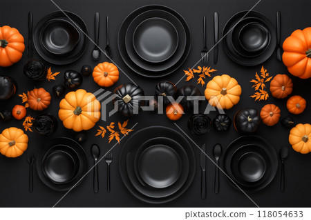 Halloween themed table setup with orange pumpkins, black skulls, red leaves, and black cutlery on a dark background Halloween themed table setup with orange pumpkins, black skulls, red leaves, and black cutlery on a dark background 118054633