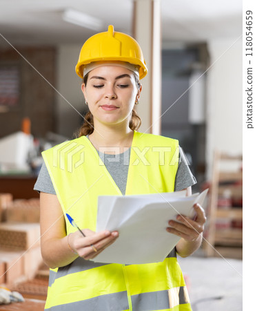 Female architect taking notes in building under renovation Female architect taking notes in building under renovation 118054659