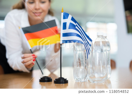 Unrecognizable girl sets midget flags of Greece and Germany before international negotiations Unrecognizable girl sets midget flags of Greece and Germany before international negotiations 118054852