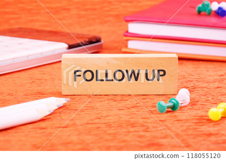 Business concept. Copy space. The words Follow Up on a wooden bar in front of an orange background, front view Business concept. Copy space. The words Follow Up on a wooden bar in front of an orange background, front view 118055120