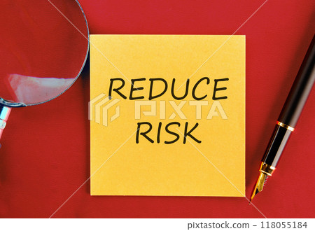 Conceptual reduce risk symbol. Copy space. Words REDUCE RISK on a yellow sticker on a red saturated background 118055184