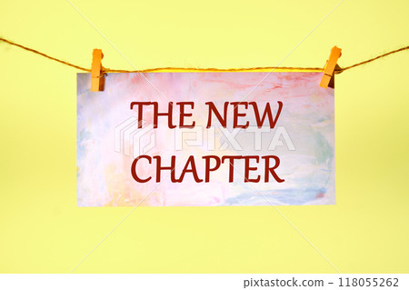 Conceptual the new chapter symbol. Copy space. The new chapter words written on a piece of paper in a clothespin on a rope on a yellow background Conceptual the new chapter symbol. Copy space. The new chapter words written on a piece of paper in a clothespin on a rope on a yellow background 118055262