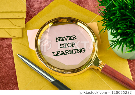 Never stop learning written on a piece of paper from an envelope through a magnifying glass Never stop learning written on a piece of paper from an envelope through a magnifying glass 118055282