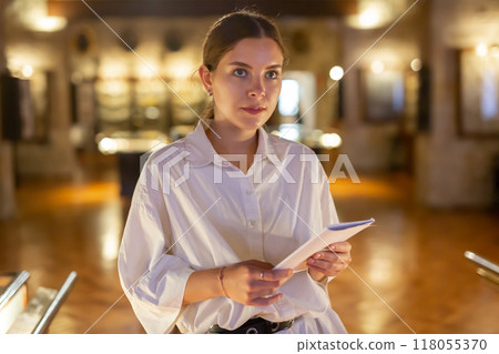 Young woman with information booklet visiting museum Young woman with information booklet visiting museum 118055370