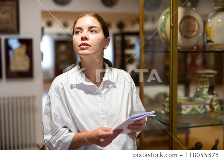 Woman visiting sculpture hall in museum and looking at exhibits 118055373
