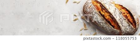 A freshly baked loaf of wheat bread sits on a white background, with wheat stalks scattered around it. Generative AI 118055753