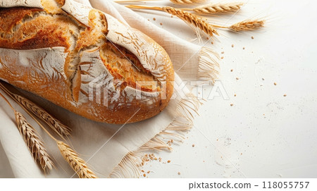 A freshly baked loaf of bread sits on a white surface with wheat stalks scattered around it. Generative AI 118055757