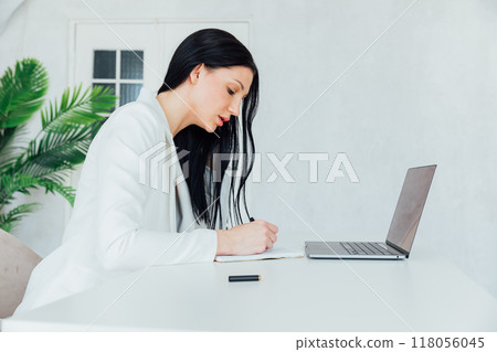 Girl woman in white suit working on laptop online in office Girl woman in white suit working on laptop online in office 118056045