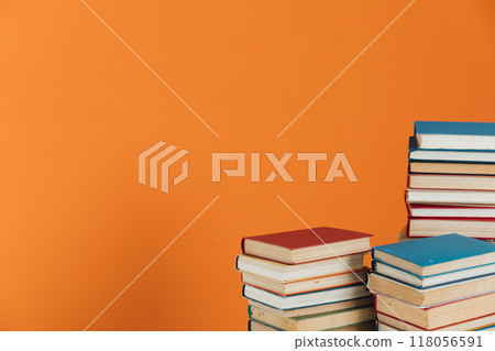 Piles of books for study in the library on an orange background Piles of books for study in the library on an orange background 118056591