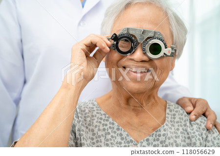 Asian senior woman wearing ophthalmic vision eye test and using optical trial frame. 118056629