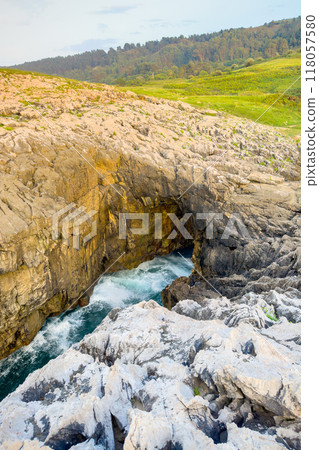 Famous natural sea cave at Llanes Asturias, Spain. landscape of the waves splashing at a natural Famous natural sea cave at Llanes Asturias, Spain. landscape of the waves splashing at a natural 118057580