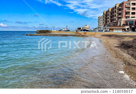 View of the promenade in Marsalforn Bay  (Salt Pans) at Gozo, Malta at sunny day with some clouds 118058017