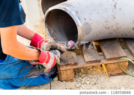 The worker prepares the edge of the weld joint for subsequent welding of the pipe The worker prepares the edge of the weld joint for subsequent welding of the pipe 118058666