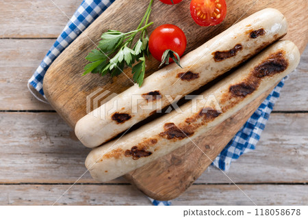 Grilled bratwurst sausages with tomatoes on wooden tabke 118058678
