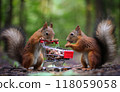Two red squirrels near the small shopping cart with nuts 118059058