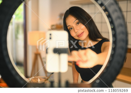 Beautiful young female blogger recording video vlog about healthy nutrition on smartphone in the kitchen 118059269