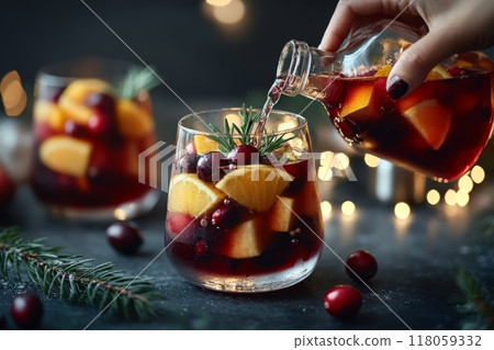 Female Hand Pouring Holiday Sangria in Glasses with Fruit Slice, Cranberry, and Rosemary on Dark Christmas Background Female Hand Pouring Holiday Sangria in Glasses with Fruit Slice, Cranberry, and Rosemary on Dark Christmas Background 118059332
