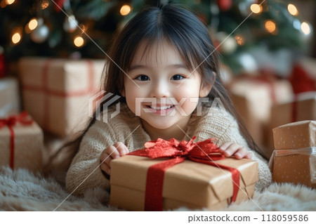 Happy Child Opening Gifts Under the Christmas Tree in a Cozy Modern Bright Interior 118059586