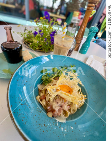 Spaghetti carbonara with bacon and egg on blue plate in restaurant 118059746