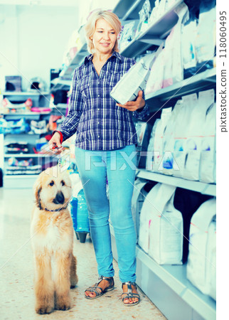 Female with Afghan Shepherd puppy choose pet food in zoo store Female with Afghan Shepherd puppy choose pet food in zoo store 118060495